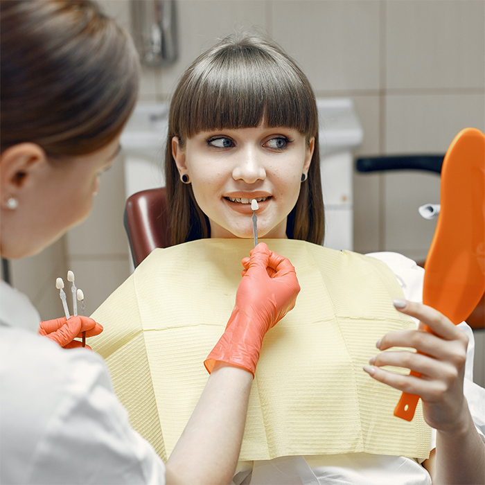 woman examining her smile in mirror after dental treatment